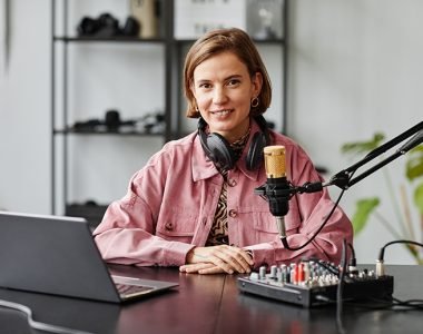 Portrait of young female creator smiling at camera in recording studio, copy space